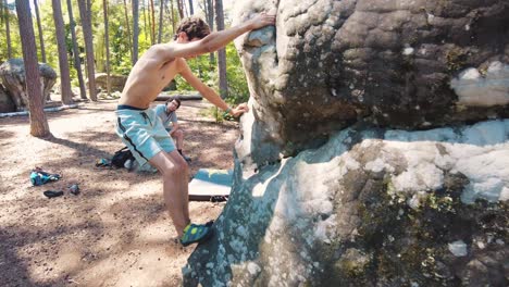 young-shirtless-teenage-boy-climbs-onto-boulder-while-dad-watches-from-the-side