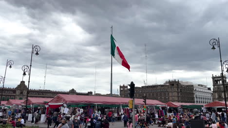 Toma-En-Cámara-Lenta-De-La-Bandera-De-México-Ondeando-Con-La-Vista-Completa-Del-Zócalo-En-El-Fondo