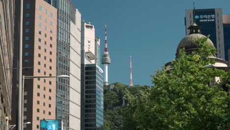 Slow-zoom-out-from-N-Seoul-tower-to-downtown-city-street-and-cars-stopped-in-traffic-jam-on-Sogong-ro-road-near-Bank-of-Korea-money-museum