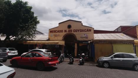 Facade,-entrance-to-the-traditional-local-Coyoacan-Market,-Streets-of-CDMX-Cars-Passing-by-Mexico-City-on-a-Sunny-day