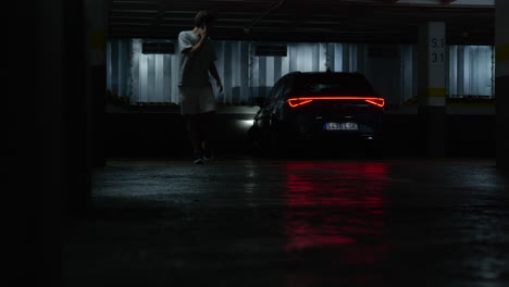 Cautious-man-walking-alone-leaving-vehicle-activating-alarm-in-eerie-underground-car-park