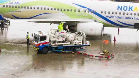 Ein-Mitarbeiter-Des-Bodenservice-Des-Flughafens,-Der-Den-Tanker-Betreibt,-Befüllt-Das-Flugzeug-An-Regnerischen-Tagen-In-Bangkok-Mit-Flugbenzin