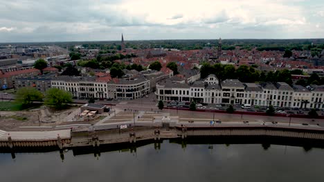 Movimiento-Aéreo-Lateral-Que-Muestra-El-Bulevar-Ijsselkade-De-La-Ciudad-De-La-Torre-Zutphen-En-Construcción-Con-Bajo-Nivel-De-Agua-Del-Río-Ijssel-En-Primer-Plano