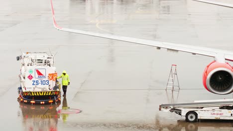 An-employee-of-the-ground-service-of-the-airport-operating-the-tanker-refills-the-aircraft-with-aviation-fuel-on-rainy-days-in-Bangkok