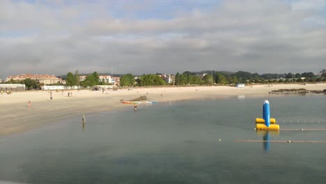 people-doing-activities-on-the-beach,-walking,-getting-wet,-canoeing,-training,-running,-sport-on-a-cloudy-summer-morning,-time-lapse-shooting