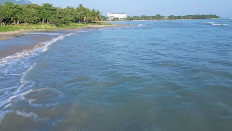 Fliegen-über-Spritzende-Meereswellen-Am-Strand-Von-Playa-Dorada-In-Puerto-Plata,-Dominikanische-Republik-Im-Sommer