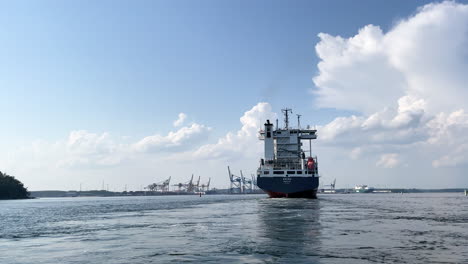 Cargo-ship-arriving-to-harbour-on-a-sunny-day-with-blue-sky-and-calm-water