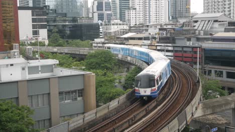 Vista-Del-Tren-Aéreo-Bts-Mientras-Pasa-Por-La-Ciudad-De-Bangkok-Bajo-El-Sol-Durante-El-Día-Con-Un-Cielo-Poco-Claro