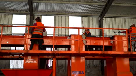 Slow-motion-pan-left-to-right-of-workers-sorting-waste-on-a-conveyor-belt