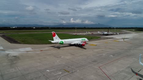 Drone-approaching-a-plane-driving-towards-the-runway,-at-a-aerodrome,-in-sunny-Mexico