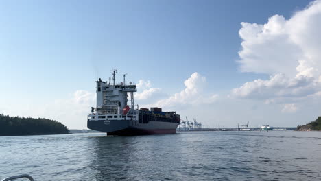 Cargo-ship-with-containers-filmed-arriving-to-harbour-from-a-sea-level-on-a-sunny-day