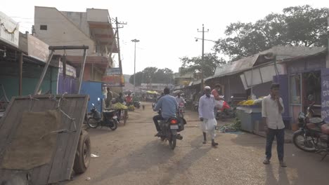 Static-slow-motion-clip-of-Asian-market,-people-and-vehicle-passing-across,-small-vegetable-vendors-and-shops-selling-vegetable-and-sweets