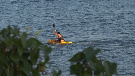 Active-man-rowing-yellow-boat-intensively,-slow-motion-distant-shot