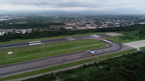 Vista-Aérea-Siguiendo-Un-Avión-En-Taxi-Moviéndose-A-La-Pista-De-Salida---Dando-Vueltas,-Tiro-De-Drones