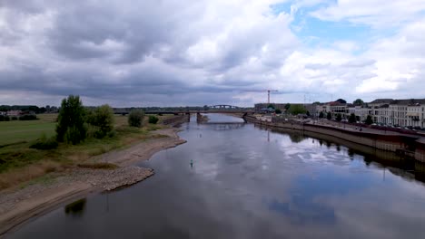 Vorwärtsbewegung-Aus-Der-Luft,-Die-Den-Niedrigen-Wasserstand-In-Der-Trockenzeit-Der-Ijssel-Am-Boulevard-Ijsselkade-Zeigt,-Der-In-Die-Schleuse-Des-Binnenschifffahrtsfrachtschiffs-In-Richtung-Stahlzugbrücke-Geht