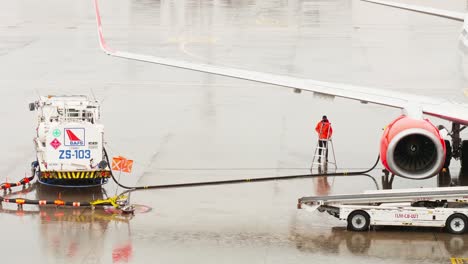 Ein-Mitarbeiter-Des-Bodenservice-Des-Flughafens,-Der-Den-Tanker-Betreibt,-Befüllt-Das-Flugzeug-An-Regnerischen-Tagen-In-Bangkok-Mit-Flugbenzin