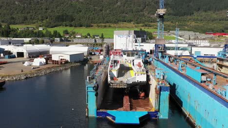 Das-Fährschiff-Befindet-Sich-In-Einem-Schwimmenden-Trockendock-Zur-Wartung-Auf-Den-Westcon-Werften-In-Olensvag,-Norwegen---Sich-Rückwärts-Bewegende-Antenne-Mit-Dem-Werftlogo-Auf-Dem-Gebäude-Im-Hintergrund