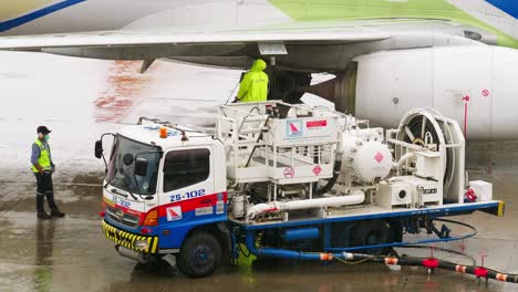 An-employee-of-the-ground-service-of-the-airport-operating-the-tanker-refills-the-aircraft-with-aviation-fuel-on-rainy-days-in-Bangkok