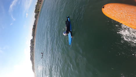 Vertical-shot-of-surfer-on-orange-surfboard,-surfing-and-falling-into-sea