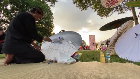 Umbrella-painting-artist,-who-is-painting-his-work-at-the-Indonesian-Umbrella-Festival