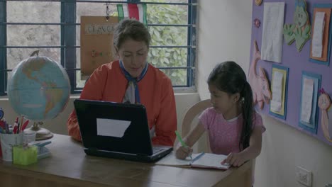 Toma-En-Cámara-Lenta-De-Un-Maestro-Educando-A-Una-Joven-Escolar-En-El-Escritorio