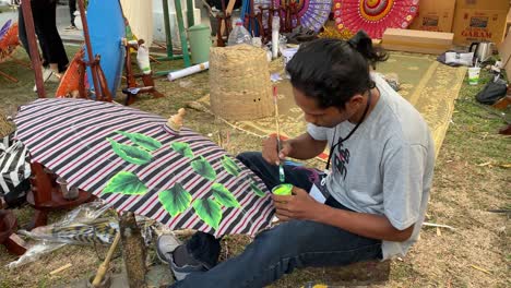 Umbrella-painting-artist,-who-is-painting-his-work-at-the-Indonesian-Umbrella-Festival