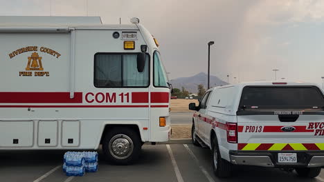 Dolly-sideways-shot-Along-Fire-department-vehicles-during-Fairview-Fire,-Sky-full-of-ashes-in-Background