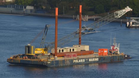 Raupenkran-Und-Andere-Baumaterialien-Werden-Auf-Einem-Lastkahn-Flussaufwärts-Verschifft