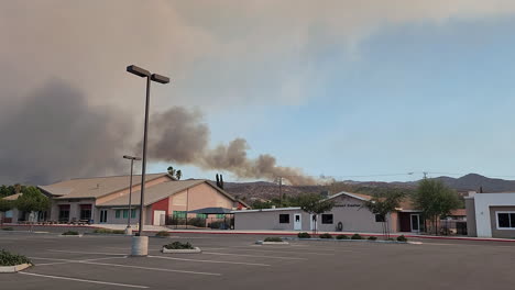 Aviones-Extinguiendo-Incendios-Forestales-En-El-Barrio-Residencial-De-Hemet-California,-Humo-Negro-Elevándose-Sobre-El-Cielo,-Ciudad-En-Los-Estados-Unidos,-Vista-Desde-El-Estacionamiento