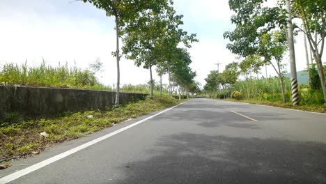 Group-of-4-women-cyclists-wearing-face-masks-and-riding-bikes-towards-camera-on-countryside-road-during-sunny-day,-filmed-as-wide-angle-shot