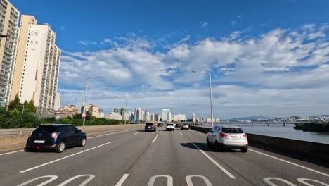 Horizonte-De-Seúl-En-El-Día-De-Verano-Perspectiva-Del-Conductor-Conduciendo-En-La-Autopista-Gangbyeonbuk-ro-En-El-Día-De-Verano-Con-Nubes-Blancas-Junto-Al-Río-Han