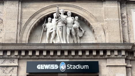 Cerrar-La-Señal-De-Entrada-Del-Estadio-Gewiss-Y-La-Estatua-Del-Edificio-Histórico