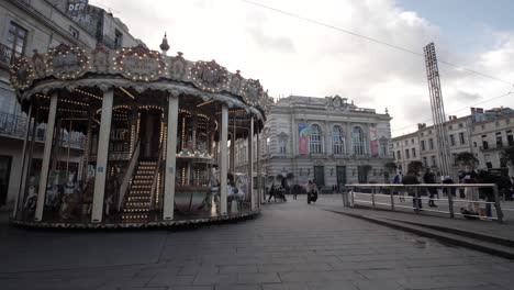 Tiro-De-Carro-Ascendente-En-Cámara-Lenta-De-Un-Carrusel-Girando-En-El-Centro-De-La-Ciudad-Con-Los-Lugareños-Pasando