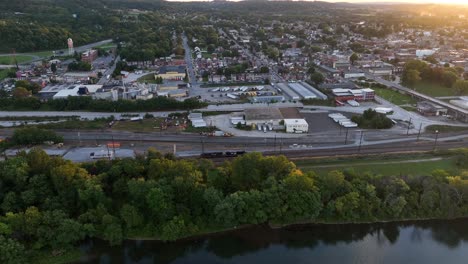 Norfolk-Southern-train-on-railroad-by-river-and-small-town-at-sunset