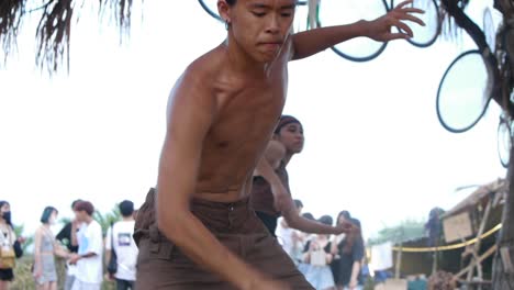 Hombre-Asiático-Sin-Camisa-Bailando-Extasiado-Durante-Un-Festival-Al-Aire-Libre,-Filmado-Como-Tiro-Medio-Con-Movimiento-De-Mano