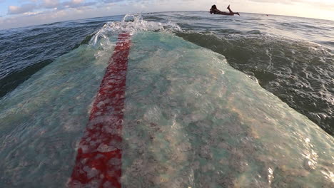 Surfer-lying-on-surfboard-swimming-towards-other-surfers,-Canggu,-Bali