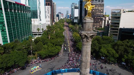 Vista-Aérea-Con-Vistas-Al-Desfile-Del-Día-De-Muertos-Detrás-De-La-Estatua-Del-ángel-De-La-Independencia,-En-La-Ciudad-De-México