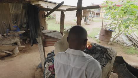 Over-the-Shoulder,-Blacksmith-Blowing-Air-unto-Hot-Coal-Fire-with-Bellow