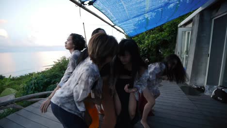 Group-of-5-Asian-women-performing-improvised-ecstatic-dance-movements-reaching-towards-sky-and-pulling-towards-earth,-filmed-as-roving-camera-with-wide-angle-lens