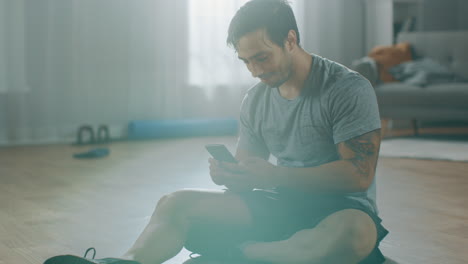 Hombre-De-Fitness-Tomando-Un-Descanso-De-Su-Ejercicio-Y-Está-Leyendo-Los-Mensajes-En-Su-Teléfono