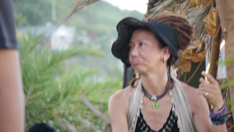 Asian-woman-with-dreadlocks-performing-ecstatic-dance-during-outdoor-music-festival,-filmed-in-handheld-style-as-tight-medium-shot