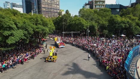 Gente-Viendo-Un-Convoy-De-Camiones-Decorados-En-El-Desfile-Del-Día-De-Los-Muertos,-En-La-Soleada-Ciudad-De-México---Vista-Aérea