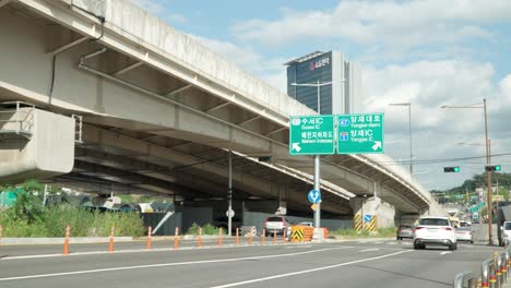 Seoul-city-traffic-time-lapse-at-Yangjae-daero-road-by-the-bridge-junction-with-a-view-of-LG-Electronics-Seocho-research-and-development-campus-center,-cloudy-summer-day