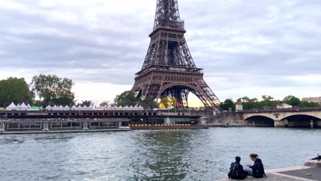 Pareja-Pasar-El-Rato-En-La-Orilla-Del-Río-Sena,-Cerca-Del-Pont-D&#39;iéna-Y-La-Torre-Eiffel-En-París,-Francia