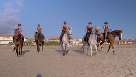 Grupo-De-Mujeres-Ecuestres-Montando-Caballos-En-La-Playa-En-Cámara-Lenta-Durante-La-Luz-Del-Sol-Y-El-Cielo-Azul---Cerrar