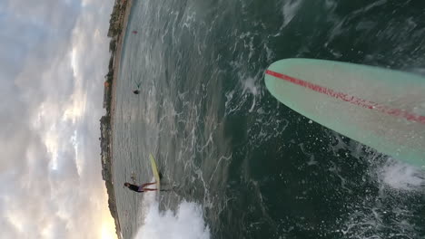 Surfing-party-wave-near-exotic-coastline-with-cloudy-sky,-POV-view