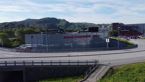 Moviéndose-Hacia-El-Edificio-Del-Centro-Comercial-Asane-Entre-Las-Banderas-Del-Centro-Comercial-Horisont---Dos-Centros-Comerciales-En-Competencia-En-Asane-Fuera-De-Bergen,-Noruega