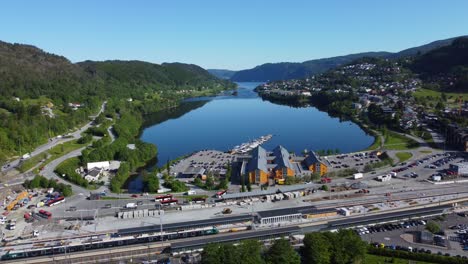 Beautiful-idyllic-Arna-and-Arnavaagen-fjord-outside-Bergen-Norway---Bus-terminal-and-VY-train-on-station-in-lower-frame-with-shopping-mall-Oyrane-torg-in-middle-and-fjord-with-mountains-background