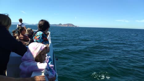 passengers-on-the-deck-of-the-ship-sailing-to-the-Cíes-Islands,-Rías-Baixas-with-the-islands-and-horizon-in-the-background,-day-cleared-and-sunny,-shot-blocked,-Pontevedra,-Galicia,-Spain