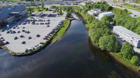 Arna-Salmon-River-Außerhalb-Von-Bergen-Im-Sommer---Birdseye-Antenne-Mit-Blick-Auf-Die-Glasige-Wasseroberfläche-Des-Flusses-In-Der-Nähe-Des-Parkplatzes-Und-Des-Stadtgebiets